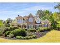Charming brick home featuring lush landscaping, a covered porch, and classic architectural details at 202 Carrington Estates Ct, Woodstock, GA 30188