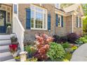 Close-up of landscaping and entrance featuring brick exterior and decorative blue shutters at 202 Carrington Estates Ct, Woodstock, GA 30188