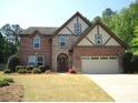 Charming two-story brick home with stone accents and a well-manicured lawn on a sunny day at 3215 Trowbridge Dr, Cumming, GA 30040