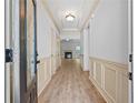 Inviting hallway featuring wood floors and decorative wall paneling, leading to a cozy living space at 2075 Villa Spring Ct, Dacula, GA 30019