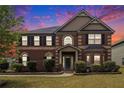 Charming two-story brick home featuring manicured landscaping and a welcoming front porch under a sunset sky at 640 Parkside Place Dr, Mcdonough, GA 30253