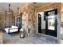 Inviting covered porch features a cozy swing and unique stone brickwork leading to the home's entry at 12640 Hearthstone Way, Alpharetta, GA 30009