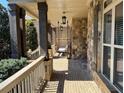 Covered porch showcases brick flooring, stone pillars, and a comfortable swing creating a relaxed outdoor space at 12640 Hearthstone Way, Alpharetta, GA 30009