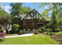 Charming Tudor-style home with a well-manicured lawn, beautiful landscaping, and classic architectural details at 937 E Rock Springs Ne Rd, Atlanta, GA 30306