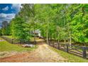 Gravel driveway leading to the home, surrounded by lush greenery and a charming black fence at 1080 Gaithers Rd, Mansfield, GA 30055