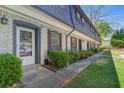 Side angle of a townhouse featuring clean white brick, traditional dark shutters, and green shrubbery at 305 Stonecliff Ct, Stone Mountain, GA 30083