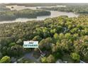 Overhead shot of the house surrounded by lush trees near a lake and the home address at 2062 Skyhawk at 2062 Skyhawk Ln, Acworth, GA 30102