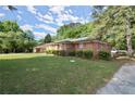 A side angle view of a charming brick home with green lawn and mature trees at 2844 Whispering Hills Dr, Chamblee, GA 30341