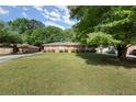 A view of the well-maintained front yard of a traditional brick home with mature trees at 2844 Whispering Hills Dr, Chamblee, GA 30341