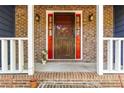 Inviting brick entryway with a red-trimmed brown front door, enhanced by sidelights and sconces at 5272 Cumberland Way, Stone Mountain, GA 30087