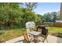 Outdoor patio with a table, chairs, and a grill surrounded by mature trees and greenery at 2014 Anchor Way, Buford, GA 30518