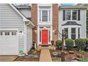 Close-up of a well-maintained home with a bright red door, gray siding, brick accent, and professional landscaping at 4272 Glenlake Nw Dr, Kennesaw, GA 30144