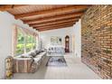 Spacious living room with exposed wood beam ceilings, brick accent wall and large window at 881 Rockbridge Sw Rd, Lilburn, GA 30047