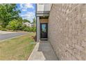 Side entrance of home with brick facade, storm door, manicured lawn, and charming walkway at 1385 Vayda Ct, Marietta, GA 30066