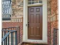 Close-up of a stylish brown front door framed by brick and stone with a black iron handrail at 346 Ardmore Ct, Atlanta, GA 30309