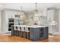 Spacious kitchen features a large island with pendant lighting and a wine rack at 560 Brook Manor Dr, Johns Creek, GA 30022