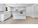 Modern kitchen with white cabinets, a center island, stainless steel appliances, and light wood flooring at 3321 Burkston Pl, Buford, GA 30519