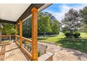 Inviting covered porch with stone flooring, wooden pillars, and serene view of lush landscaping and a long driveway at 4392 Lower Fayetteville Rd, Sharpsburg, GA 30277