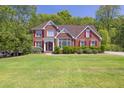 Beautifully landscaped brick home with lush green lawn and mature trees at 2945 Barimore Pl, Dacula, GA 30019