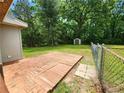 Spacious backyard with a wooden patio, chain link fence, storage shed, and mature trees at 4030 Hiram Ct, Powder Springs, GA 30127