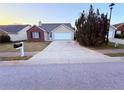 Attractive single-story home with a brick detail, an attached garage, and a long concrete driveway at 11447 Vinea Ln, Hampton, GA 30228