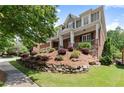 Charming home featuring a stone retaining wall, manicured lawn, and a inviting front porch at 1286 Whisper Cove Dr, Buford, GA 30518