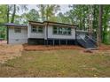 The back of a beautiful renovated home featuring a spacious deck and serene wooded lot at 1329 Hidden Hills Pkwy, Stone Mountain, GA 30088