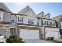 Desirable townhome showing off a two-car garage, gray and brick exterior, and manicured lawn at 2946 Stockholm Way, Suwanee, GA 30024