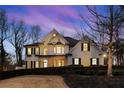 Stunning home with manicured landscaping, brick exterior, and black shutters against a twilight sky at 5120 Post Oak Tritt Ne Rd, Roswell, GA 30075
