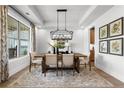 Elegant dining room with tray ceiling, modern chandelier, and large window offering natural light at 313 Brooke View Trl, Canton, GA 30115
