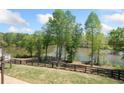 A scenic backyard with lush green grass, a black fence, and serene lake views at 4180 Woodwind Dr, Cumming, GA 30028