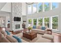 Bright living room with a stone fireplace, hardwood floors, and large windows with lake views at 4180 Woodwind Dr, Cumming, GA 30028