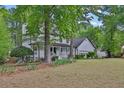 Two-story white home with a charming front porch, surrounded by mature trees and green grass at 191 Gates Mill Dr, Lawrenceville, GA 30045