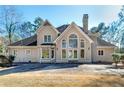 Back exterior view with large windows offering ample natural light, set against a backdrop of mature trees at 2009 Pine Forest Ct, Jonesboro, GA 30236