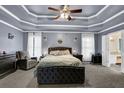 Spacious main bedroom with tray ceilings, plush carpeting, and an adjoining ensuite bathroom at 92 Creek Front Way, Lawrenceville, GA 30043