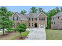 Charming two-story brick home with lush front yard landscaping, a three-car garage, and double driveway at 4395 Wildbrooke Pkwy, Cumming, GA 30041