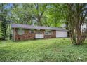 Inviting single-story brick home with a two-car garage, shaded by mature trees and a lawn with greenery at 2412 Forrest Park Se Rd, Atlanta, GA 30315