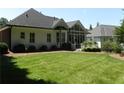 Expansive backyard featuring lush green grass, mature landscaping, and a sunroom with lots of light at 4019 Hickory Fairway Dr, Woodstock, GA 30188