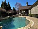 Backyard pool with stone deck, waterfall feature and covered outdoor seating area at 216 Slate Dr, Buford, GA 30518