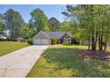 Suburban home with a two-car garage and a well-maintained lawn surrounded by lush green trees under a bright sky at 5630 Tallantworth Xing, Cumming, GA 30040