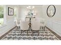 Bright dining room features a modern chandelier, wainscoting and stylish black and white rug at 1129 Georgian Point Dr, Lawrenceville, GA 30045