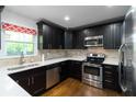 Modern kitchen with stainless steel appliances, dark cabinetry, and stone tile backsplash at 2218 Edgemore Se Dr, Atlanta, GA 30316