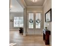 Bright foyer boasts hardwood floors, double doors adorned with wreaths, and elegant decor creating a grand entrance at 86 Ewing Way, Dacula, GA 30019