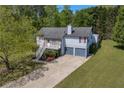 View of two-story home with gray siding and stone accents, complemented by lush trees and a driveway at 582 Linda Ln, Powder Springs, GA 30127