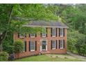 Classic brick home with black shutters and a well-manicured lawn surrounded by mature trees at 2895 Shurburne Dr, Alpharetta, GA 30022