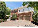 Brick home featuring a two-car garage, expansive driveway, and potential for outdoor living space at 4675 Lakeway Pl, Alpharetta, GA 30005
