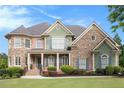 Charming stone and green two-story home featuring a landscaped yard and inviting entrance at 3820 Preserve Crossing Ln, Cumming, GA 30040