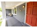 Charming covered porch with seating area and view of the front yard with red front door at 126 N Barton St, Norcross, GA 30071