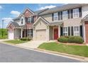 Street view of charming townhomes with garages, well-kept lawns, and inviting red doors at 2557 Avery Park Cir, Atlanta, GA 30360