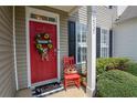 Welcoming red front door adorned with a floral wreath and a charming decorative chair at 2557 Avery Park Cir, Atlanta, GA 30360